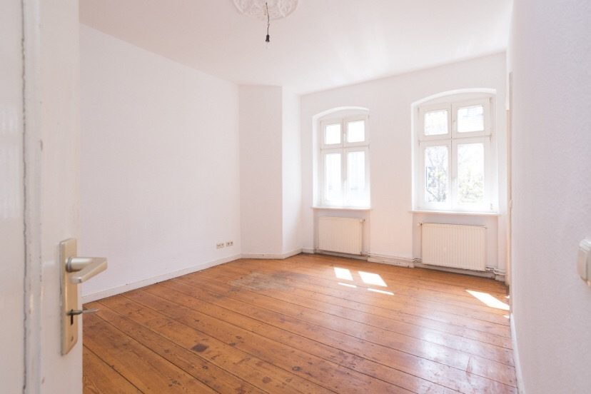 Heller leerer Raum mit Dielenboden und zwei Fenstern